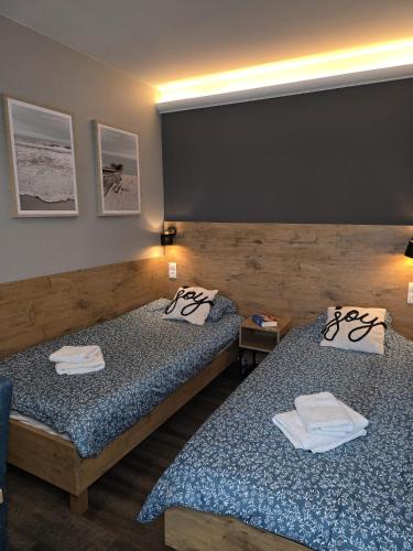 two beds in a hotel room with towels on them at Apartament KOJA in Rewal