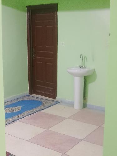 Un baño con una puerta marrón y un lavabo. en Hostel merzouga, en Merzouga