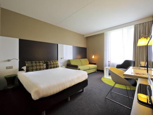 a hotel room with a bed and a couch at Mercure Hotel Zwolle in Zwolle