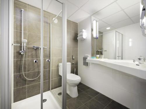 a bathroom with a shower and a toilet and a sink at Mercure Hotel Zwolle in Zwolle