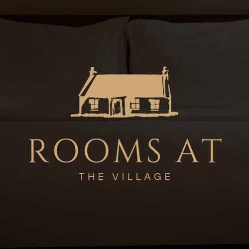 a logo for rooms at thevillage on a bed at Rooms at the Village in Omagh