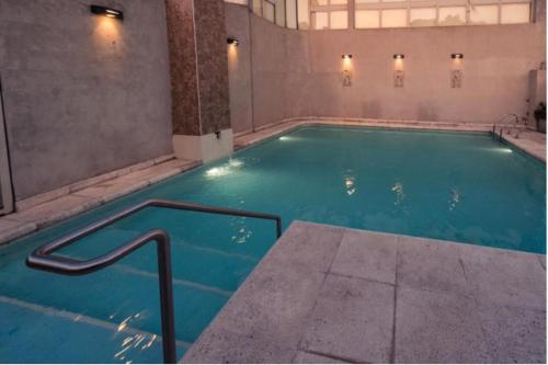 a swimming pool with blue water in a building at Apart Hotel Explora Tandil in Tandil