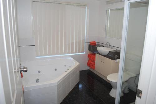 a bathroom with a tub and a toilet and a sink at Lookout Holiday Units in Lakes Entrance