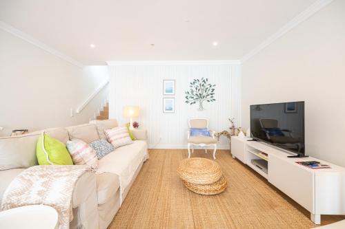 a living room with a white couch and a tv at Casa Alecrim in Tavira