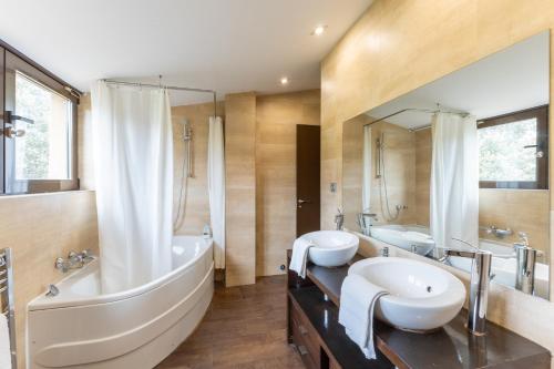 Un baño con dos lavabos, una bañera y un espejo. en El Herrén Del Abuelo, en Vegas de Matute
