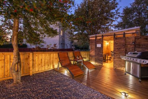 a backyard with a wooden deck with a grill and a house at Private Hot Tub - Garden - Free Parking -2bdrm - 5ppl - Zen & Bubbles in Edinburgh
