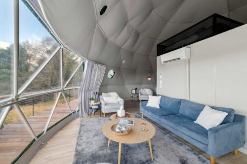 a living room with a blue couch and a table at Barrel Hot Tub at 'The Eagle Dome' in Franklin in Franklin