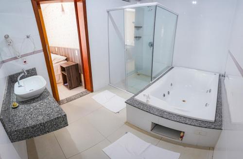 a bathroom with a shower and a tub and a sink at Garcia Palace Hotel in Sinop