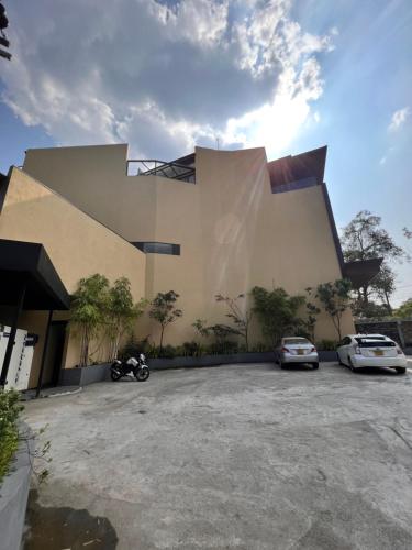 a building with two cars parked in a parking lot at Avanee Hotel in Mawanella