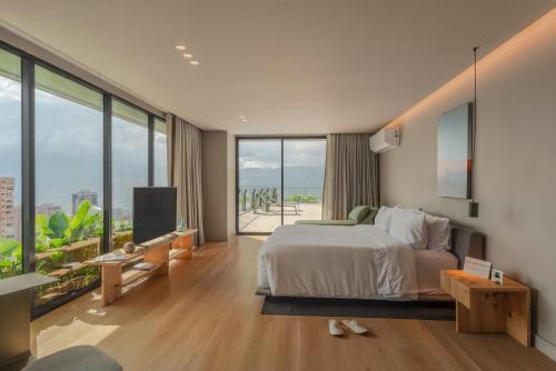 Un dormitorio con una cama grande y grandes ventanales. en Wake BioHotel, en Medellín
