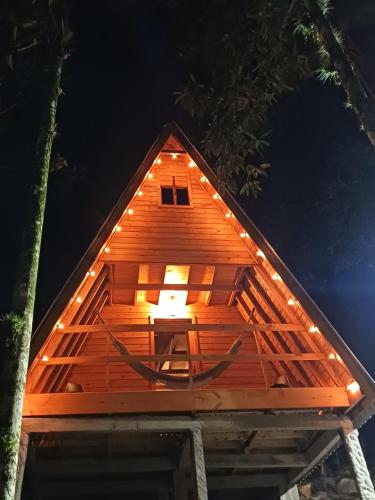 a small wooden house with lights on top of it at Chalé com jacuzzi Florianópolis in Florianópolis