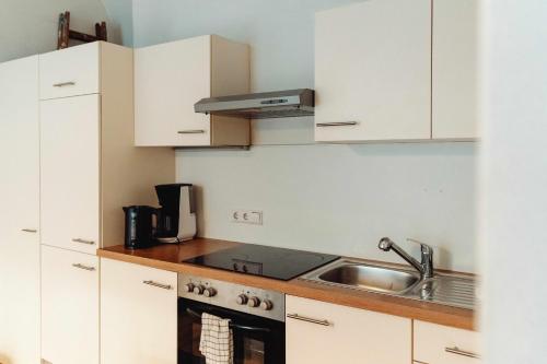 Una cocina con gabinetes blancos y un fregadero. en City Center Studio, en Graz