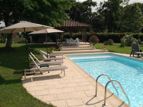 een zwembad met stoelen en parasols ernaast bij Maison d'hôtes - La Forge de Clermont in Clermont