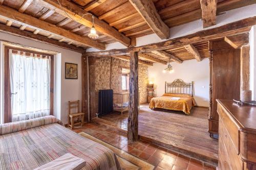 ein Schlafzimmer mit einem Bett in einem Zimmer mit Holzdecken in der Unterkunft La Botica De Maderuelo in Maderuelo