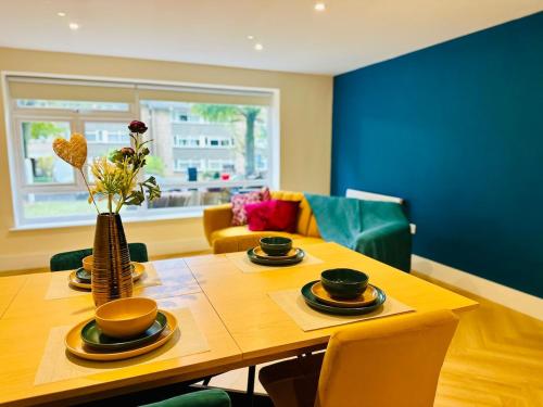a dining room with a wooden table with a vase of flowers at LivinSpace- Modern and spacious 2 bed flat in Central Sutton in Sutton