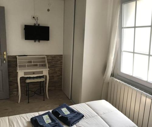 a bedroom with a bed and a desk and a television at la forge de Clermont in Clermont