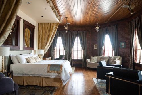 a bedroom with a bed and a couch and windows at The Hackett Hotel in Marietta