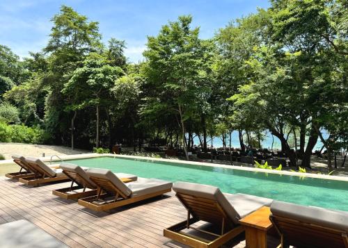 un groupe de chaises longues et une piscine dans l'établissement Monkey Villa, à Nacascolo