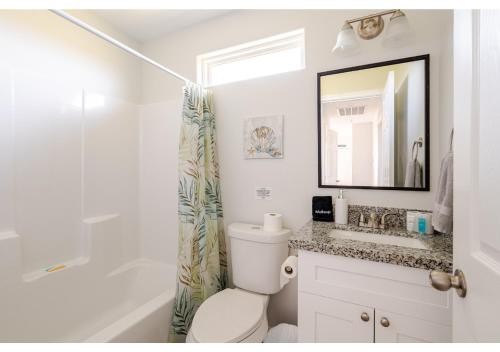 ein Badezimmer mit Toilette, Waschbecken und Spiegel in der Unterkunft Blue Lagoon with Hot Tub and Golf Cart! in Bolivar Peninsula