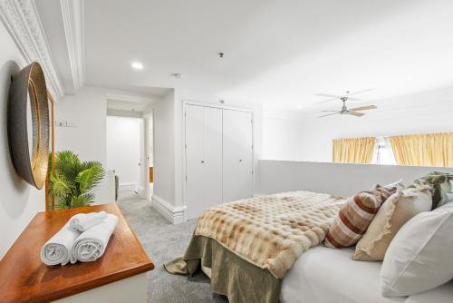 a white bedroom with a bed and a table at Character Central in Christchurch