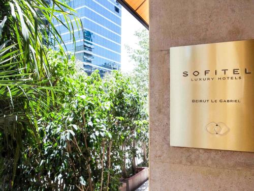 a sign on the side of a building with trees at Sofitel Beirut Le Gabriel in Beirut