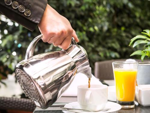 a person pouring coffee into a cup on a table at Sofitel Beirut Le Gabriel in Beirut