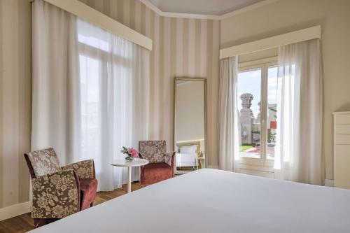 a bedroom with a large white bed and two chairs at NH Collection Madrid Abascal in Madrid