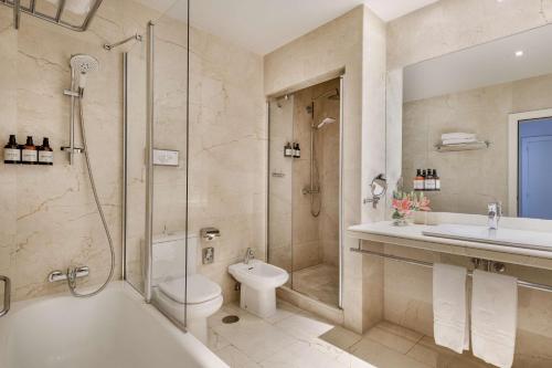 a bathroom with a tub and a toilet and a sink at NH Collection Madrid Abascal in Madrid