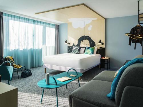ルーヴァン・ラ・ヌーヴにあるibis Styles Louvain-la-Neuve Hotel and Eventsのベッドとソファのあるホテルの部屋