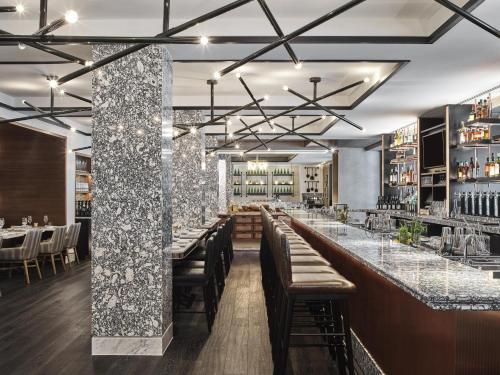 a restaurant with a long bar with tables and chairs at Hamilton Hotel - Washington DC in Washington, D.C.