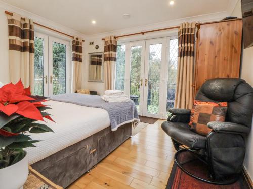 a bedroom with a bed and a leather chair at Freshwinds in Market Drayton