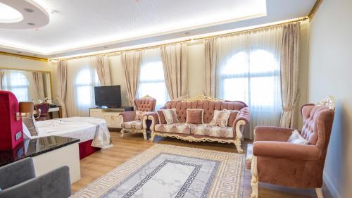a living room with a couch and chairs and a tv at can palace adalya otel in Antalya