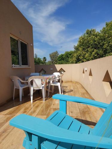 un patio con sedie e tavoli blu su un tetto di בדרך לנחל a Sde Nehemia