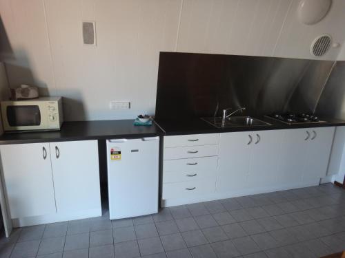a kitchen with white cabinets and a black counter top at Fremantle Village in Fremantle