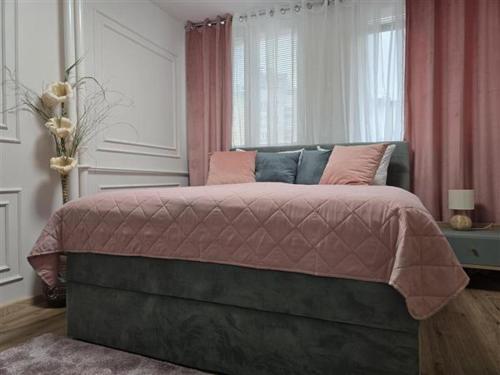a bedroom with a bed with pink pillows and a window at Apartman Karamelica in Užice