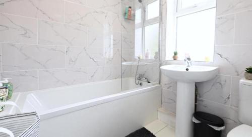 a bathroom with a white tub and a sink and a bath tubermottermottermott at The Stadium Rooms Elegant and Comfy Stay in London