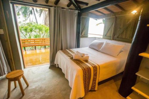 ein Schlafzimmer mit einem Bett und einem großen Fenster in der Unterkunft Casa 4 suítes - Vista para Barra do Sahy in São Sebastião