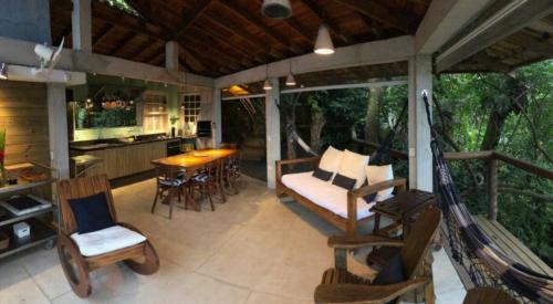 eine Veranda mit einer Schaukel, einem Tisch und Stühlen in der Unterkunft Casa 4 suítes - Vista para Barra do Sahy in São Sebastião