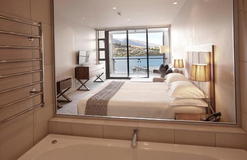 a hotel room with a large bed and a large window at The Rees Hotel & Luxury Apartments in Queenstown