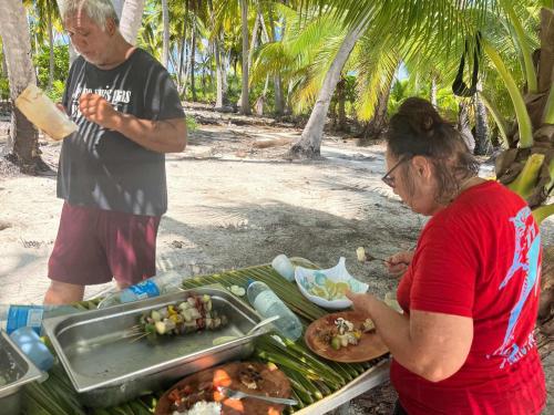 a man and a woman standing next to a buffet of food at Monita Villa Rangiroa in Tiputa