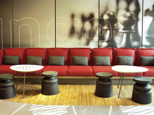 a red couch with two tables and two stools at ibis Paris Saint-Denis Stade Sud in Saint-Denis