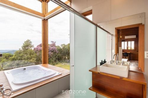 a bathroom with a large tub and a large window at Cabana c/ vista panorâmica e jacuzzi - VST026 in São Paulo dos Pinhais
