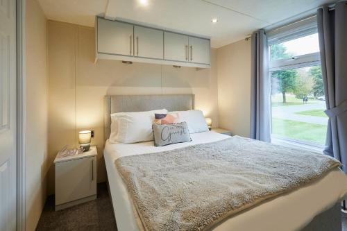 Barmby on the MoorにあるLucas Lodge with Hot Tubのベッドと窓のある小さな寝室