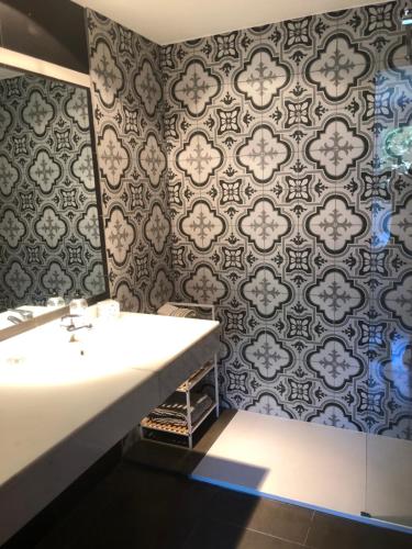 een badkamer met een wastafel en een muur met patronen bij Standing Apartment Barcelona Forum in Sant Adria de Besos