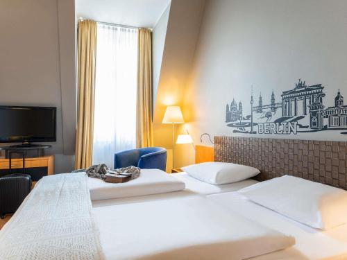 um quarto de hotel com duas camas e uma TV em Mercure Hotel & Residenz Berlin Checkpoint Charlie em Berlim