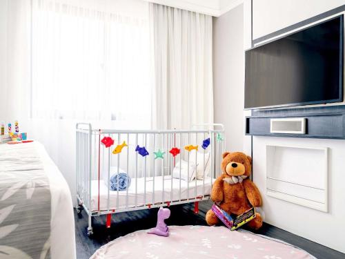 a teddy bear sitting in a crib in a bedroom at Mercure São Paulo Ibirapuera Privilege in Sao Paulo
