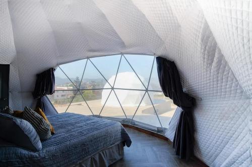 un lit dans une chambre avec une grande fenêtre dans l'établissement Cupulas Del Valle by Villa De La Rosa WiFi & AC Suite 5, à San Pablo