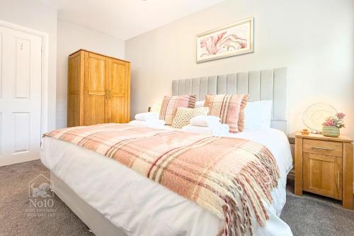 ein Schlafzimmer mit einem großen Bett und einem Holzschrank in der Unterkunft Central, dog friendly, private courtyard in Edwinstowe