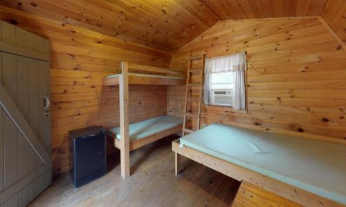 een houten hut met 2 stapelbedden en een raam bij Jellystone Park PA Wilds in Mansfield