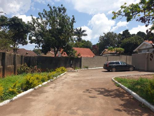 a car parked in a parking lot next to a fence at KBK COMFORT Accommodation in Kampala